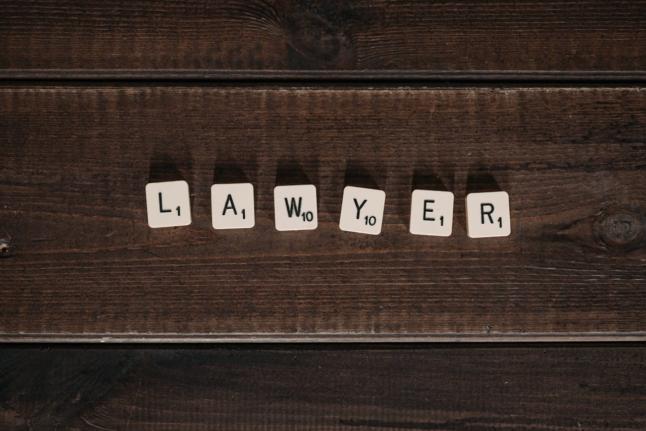 Close-up of scrabble tiles spelling 'lawyer' on a dark wooden surface.